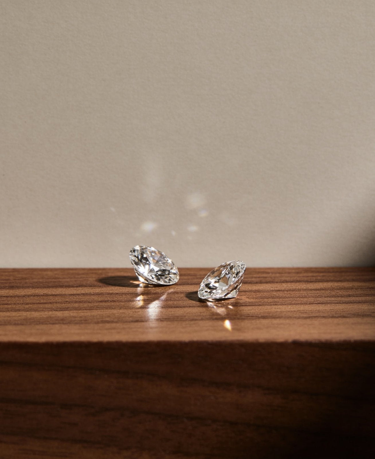 Two loose lab-grown diamonds catching the light on a wooden table