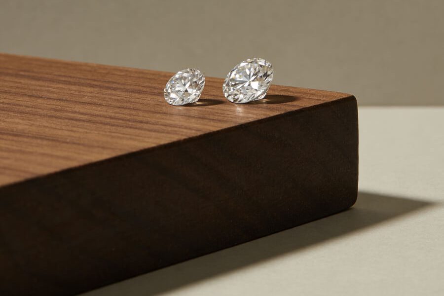 Two loose lab-grown diamonds facing up white on a walnut block